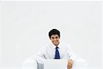 Businessman sitting on armchair using laZSop, smiling at camera