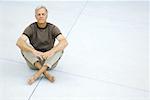 Älterer Mann sitzt indischen Stil auf dem Boden, die Augen geschlossen