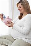 Pregnant Woman Putting Money in Piggy Bank