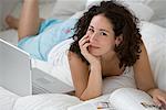 Woman with Laptop and Magazine on Bed