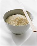 Un bol de riz blanc cru avec des baguettes