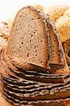 Slices of farmhouse bread in a pile in front of assorted rolls