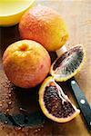 Blood oranges, whole and two wedges, on chopping board