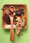 Various dried chili peppers in wooden bowl