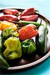 Various chili peppers on wooden plate