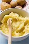 Mashed potato in bowl with wooden spoon