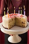 Femme qui dessert gâteau d'anniversaire avec des bougies allumées