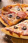 Pizza mit Salami, Käse und Oliven, Schnitt Stücke