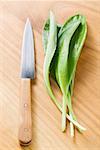 Fresh ramsons (wild garlic) on wooden background with knife