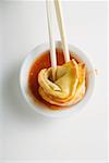 Dipping a deep-fried wonton in sweet and sour sauce