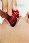 Woman biting into a strawberry