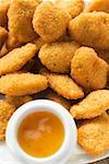 Many chicken nuggets with apricot sauce on plate