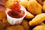 Dipping a chicken nugget in ketchup