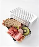 Ham sandwiches, radish and kiwi fruit in lunch box