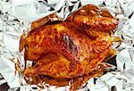 Half a grilled chicken on aluminium foil