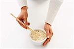 Woman’s hands holding chopsticks in a bowl of rice (1)