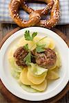 Burgers on potato and cucumber salad with pretzel