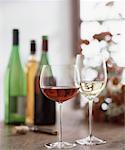 Gläser von roten und weißen Wein, Wein-Flaschen im Hintergrund