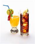 Orangeade garnished with fruit, cola with ice cubes