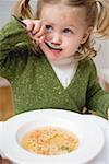 Kleines Mädchen mit Teddybär Nudeln Suppe essen