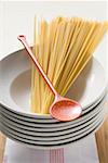 Spaghetti with cooking spoon on pile of plates