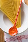 Spaghetti with cooking spoon on pile of plates