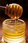 Honey running from honey dipper into honey jar