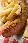 Currywurst with chips in a paper dish