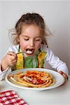 Small girl eating macaroni with tomato sauce and Parmesan