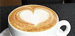 A cup of cappuccino with milk foam decorated with heart