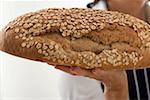 Woman holding a loaf of oat bread on the flat of her hand