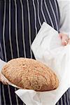 Woman wrapping a loaf of oat bread in paper