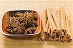 Star anise in wooden bowl, cinnamon sticks beside it