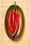 Three chili peppers in wooden bowl