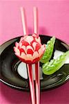 Radish flower on chopsticks, carved cucumber leaves