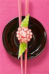 Radish flower on chopsticks, carved cucumber leaves