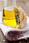 A piece of spinach and ricotta pie beside bottle of olive oil