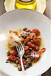 Roasted tomatoes with capers, white bread on fork, olive oil