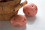 Two red potatoes beside woodchip basket