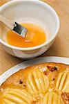 Apple cake and egg yolk in small bowl with pastry brush