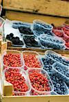 Various types of berries in plastic punnets at a market