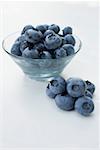 Blueberries in and beside a glass bowl