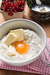 Farine, beurre, œufs dans un bol, groseilles et cuisson étain