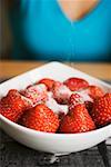 Saupoudrer de sucre sur les fraises dans un bol blanc