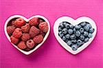 Raspberries and blueberries in heart-shaped bowl