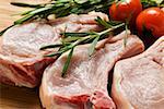 Raw pork chops with rosemary and tomatoes