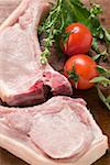 Raw pork chops, fresh herbs and tomatoes