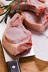 Raw pork chops with meat cleaver and rosemary