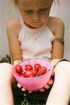 Seated girl holding bowl of fresh red cherries