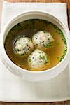 Clear broth with bacon dumplings in soup bowl